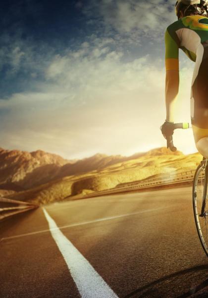 Ciclista su strada di montagna al tramonto.