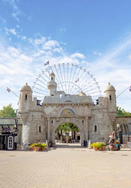 Ingresso di un parco divertimenti con ruota panoramica e castello.