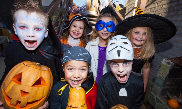 Bambini in costumi di Halloween con zucche, sorridenti e divertenti.