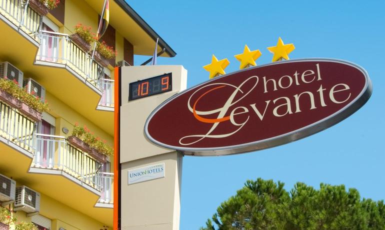 Hotel Levante, tre stelle, con balconi fioriti e orologio digitale.