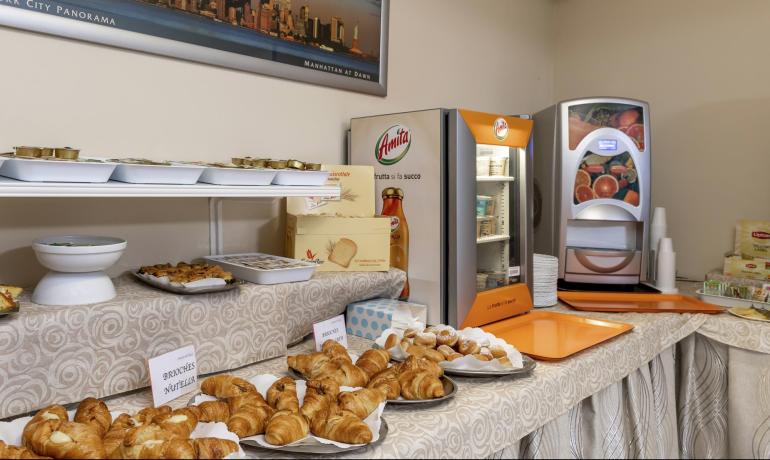 Buffet colazione con croissant, succhi e bevande calde.