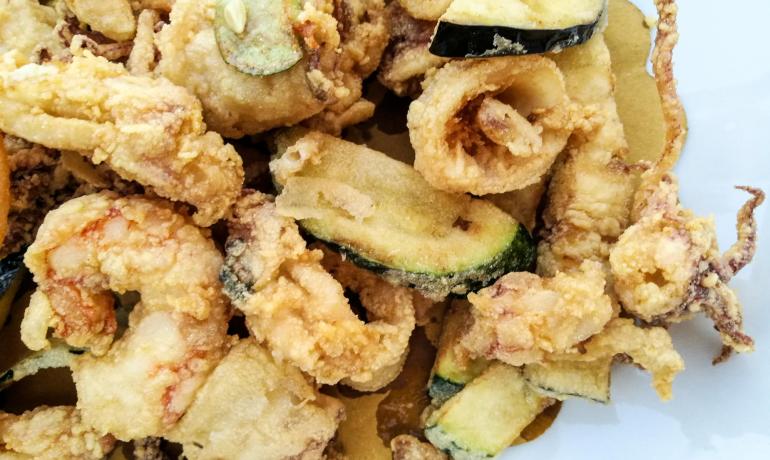 Frittura di calamari e verdure croccanti su piatto bianco.